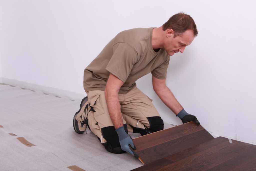 man wearing gloves while installing wood tiles