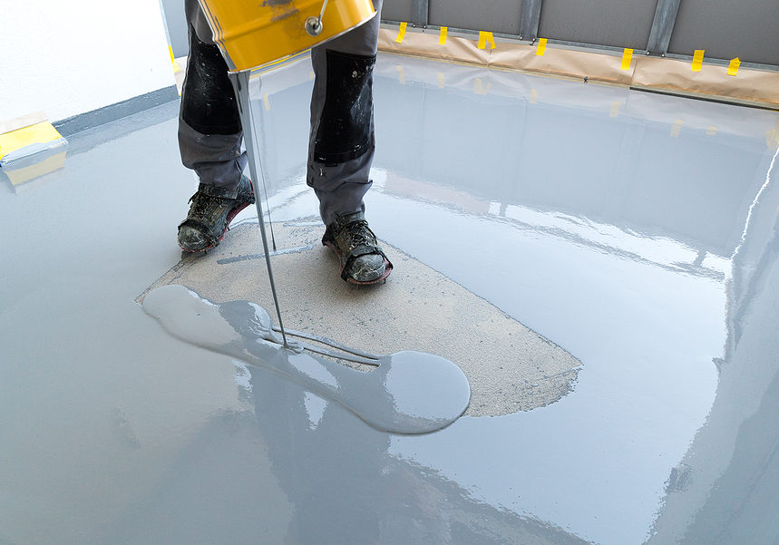 man pouring an epoxy flooring on the ground